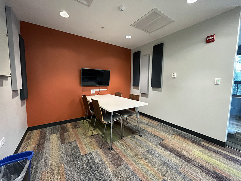 Study Room 2 showing table, four chairs, and screen with orange accent wall