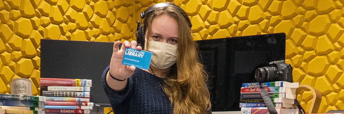 Librarian holding up library card in digital media lab room
