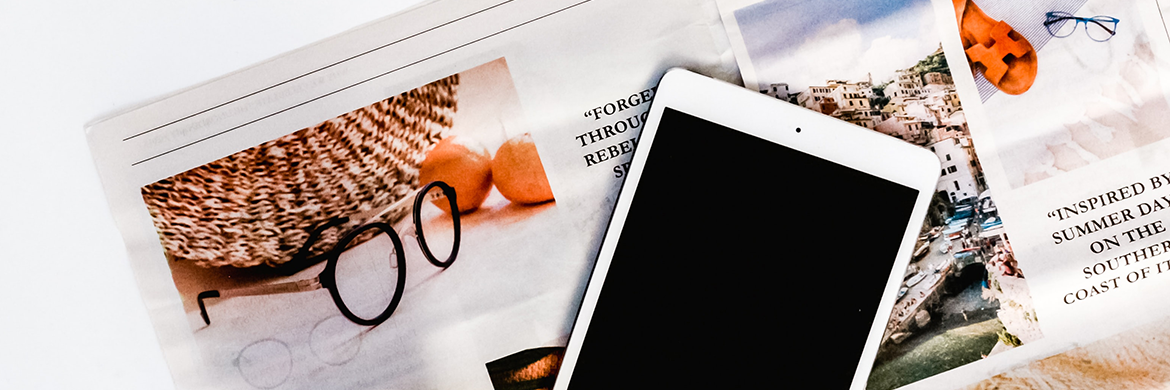 Open newspaper with tablet sitting on top