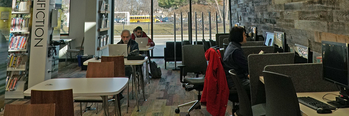 People in the adult services area using the study tables and desktop computers