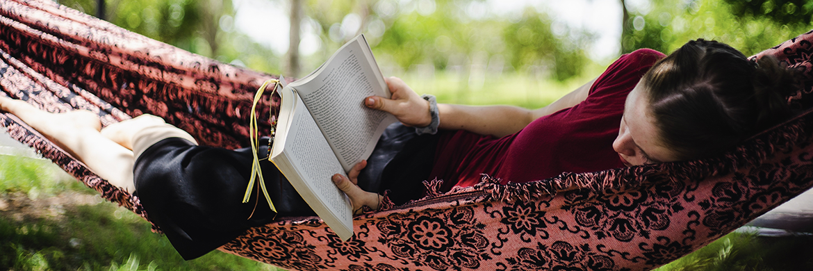 Teen girl reading book in hammock